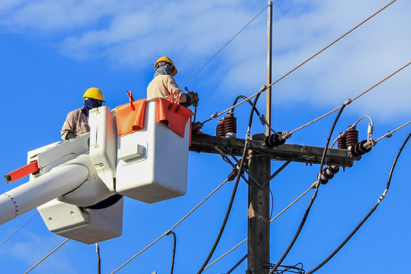 Electrical Worker in bucket lift working on electrical pole and lines